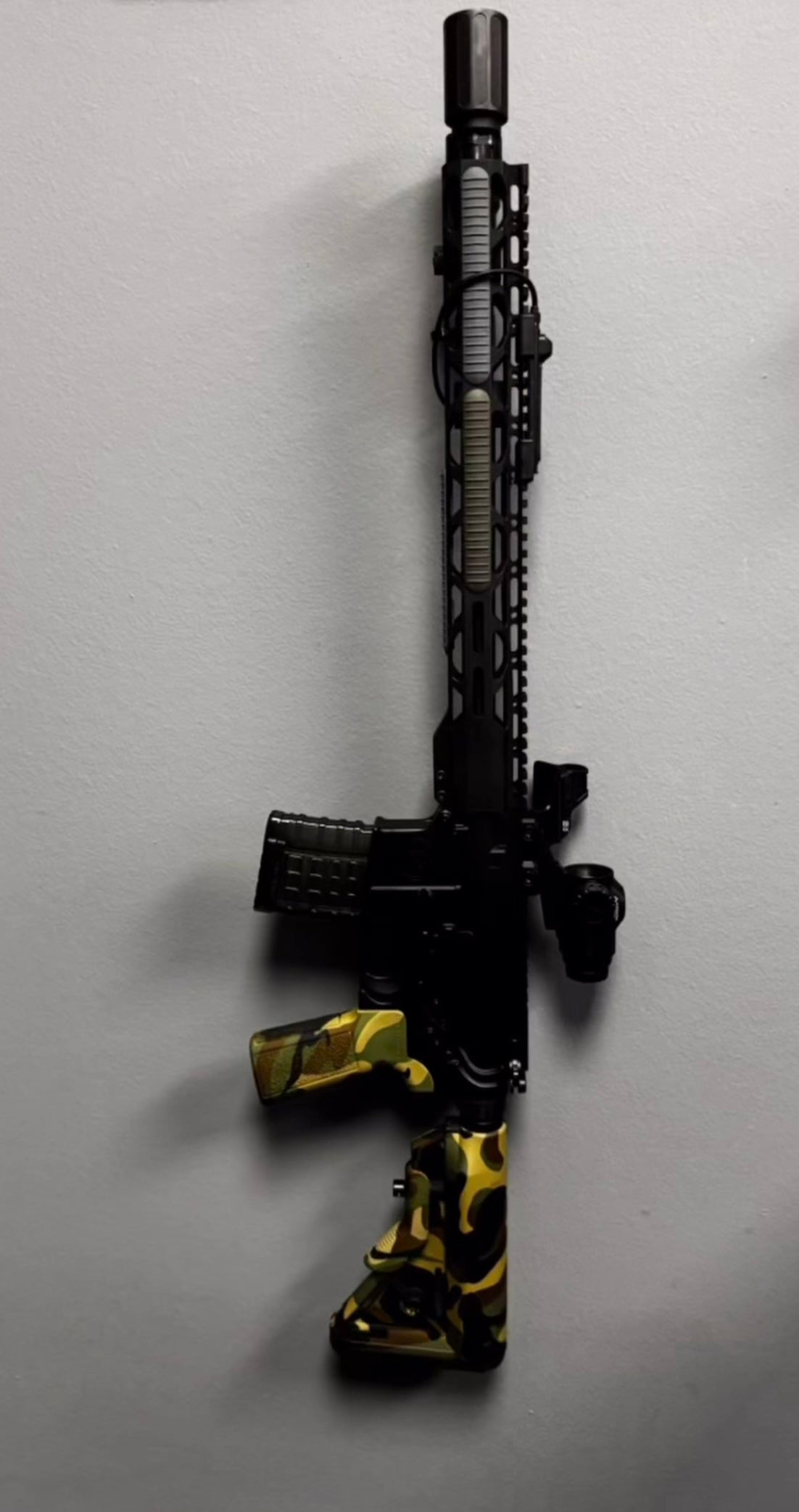 black and yellow vertical mounted rifle on white background